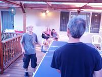 Ryan schooling Les at ping-pong while the girl's sing crazy songs