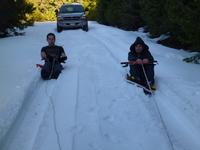 Patrick and Jerry sledding behind the car